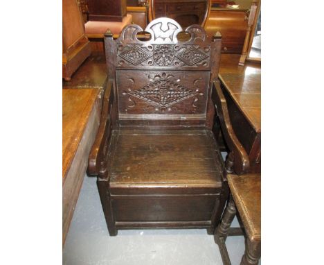 Oak Wainscot type open armchair, the carved panel back above shaped arms and a box seat with hinged lid and style supports, 1