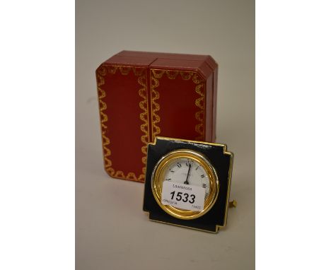 Cartier gilt brass and black painted travel alarm clock with circular dial having Roman numerals, in original fitted box with