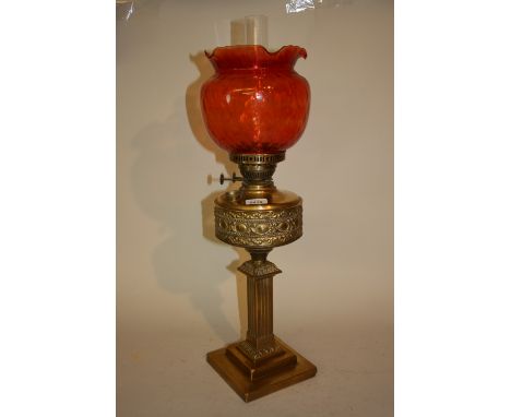 Edwardian brass oil lamp with square column and stepped plinth base and ruby glass shade