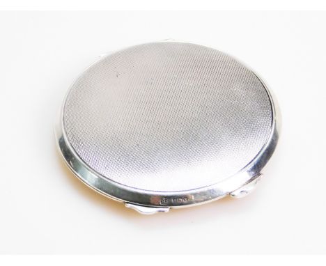 A George VI silver powder compact, of shaped circular outline, partially engine turned, the hinged lid revealing a partially 