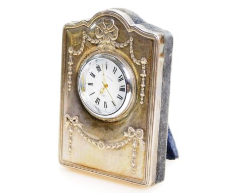 An Elizabeth II silver fronted mantel clock, raised with garlands, set with 3cm dia. Roman numeric dial, signed R Carr, Engla