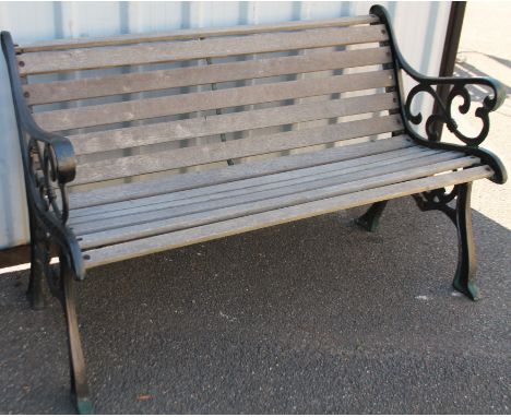 A cast metal and wooden slatted garden bench, with square fleur des lys style ends, on shaped supports, 139cm wide.