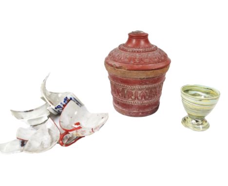 An early 19thC marble slip pottery egg cup, of typical swirl design, 6cm high, and a 19thC red glazed pottery jar and cover a
