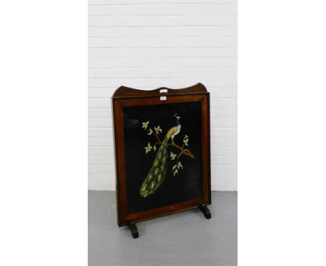 A mahogany framed fire screen with a glazed panel enclosing an embroidered depiction of a Peacock on trestle supports, 90 x 6