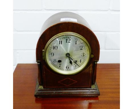 A mahogany cased dome topped mantle clock, the silvered dial with Arabic numerals, flanked by pilasters, raised on four brass