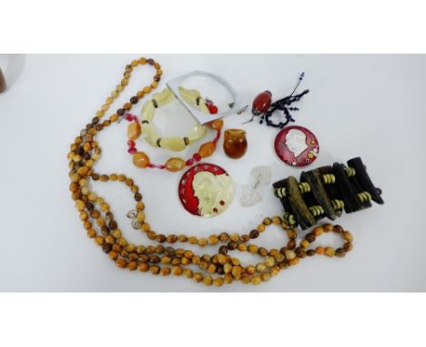 A mixed lot of costume jewellery to include a wooden bracelet and beads, enamel Chairman Mao pendant and a white metal bangle