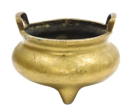 A Chinese bronze censer of twin handled circular form, raised on three tapering feet, bears sixteen character seal mark, 18cm
