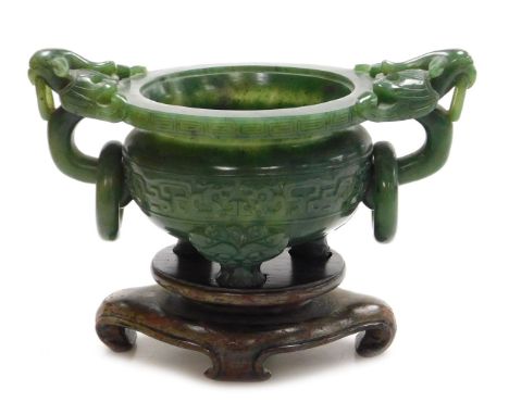 A Chinese spinach jade censer, with twin bird head and ring handles, carved with a band of stylised dragons, raised on three 