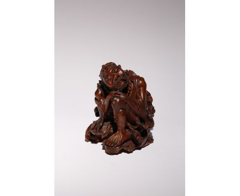 A CHINESE CARVED HARDWOOD FIGURE OF A LUOHAN 17TH/18TH CENTURY Depicted sitting, wearing loose robes tied at the waist with a