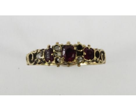 A Victorian ruby three stone ring, set with old cut diamonds at intervals, in yellow metal, size N, 1.8g.