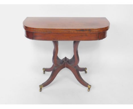 A George III mahogany fold over card table, raised on four fluted scroll supports above four fluted outswept legs, brass capp