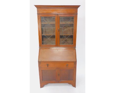 An Edwardian oak and barber pole inlaid bureau bookcase, the outswept pediment over two lead glazed doors, enclosing two shel