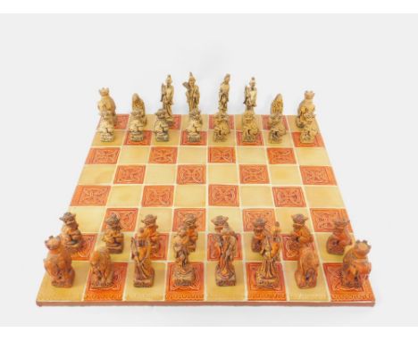 A ceramic tiled Celtic knot chess board, 54cm x 54cm, together with a set of resin chess pieces modelled as Chinese figures.
