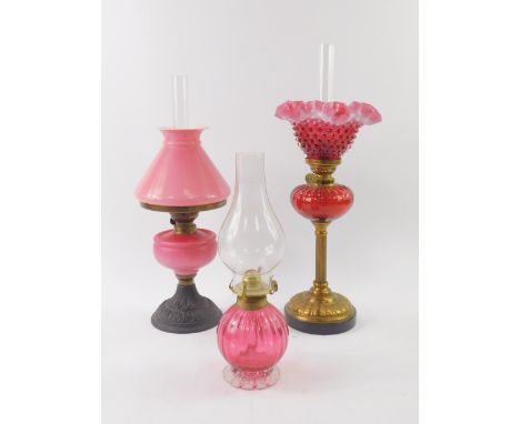 A Victorian cast iron oil lamp, with a uranium glass reservoir and pink glass shade, 42cm high, a cranberry glass oil lamp, a