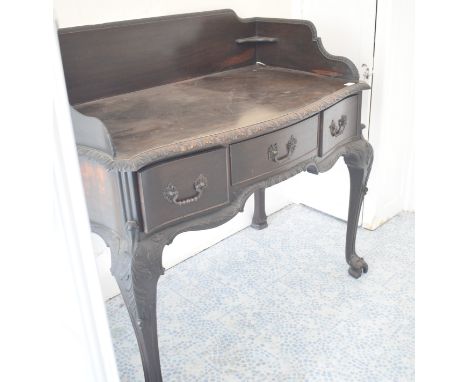 A Chippendale style mahogany dressing table, with a three quarter gallery back, three frieze drawers, and leaf carved cabriol