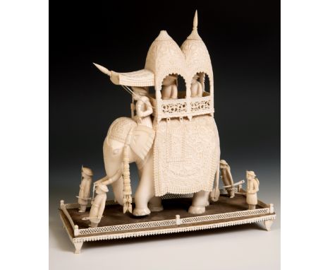 A late 19th century carved ivory elephant, carrying a howdah, carrying two figures escorted by four guards, 30 cm high x 30 c