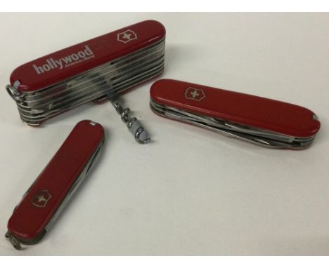 A large multi-functional Swiss army knife together with two others. Est. £100 - £150.