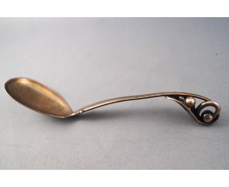A Danish white metal small serving spoon/ladle of naturalistic design, with an ovoid bowl and rib edged handle leading to a w