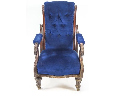 A Victorian mahogany framed armchair with hinged button back on turned and fluted tapering legs with brass casters