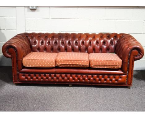 A leather two seat sofa, of Chesterfield form with three fabric upholstered seat cushions, 192cm wide 