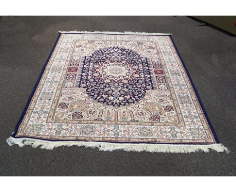 A blue ground Kohan rug, with a shaped central blue panel highlighted with flowers and foliates in a border with paisley moti