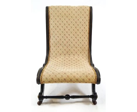 A Victorian ebonised and upholstered nursing chair with gilt metal mounts on ceramic casters