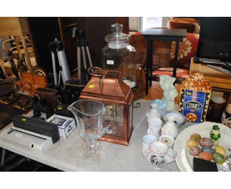 A lemonade dispenser, candle lantern, a glass jug and a leather satchel 