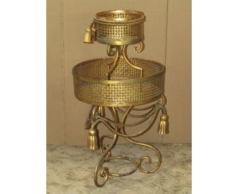 A decorative two tier iron work jardinière stand of graduated form, with rope twist and tassel detail on scrolled supports, t