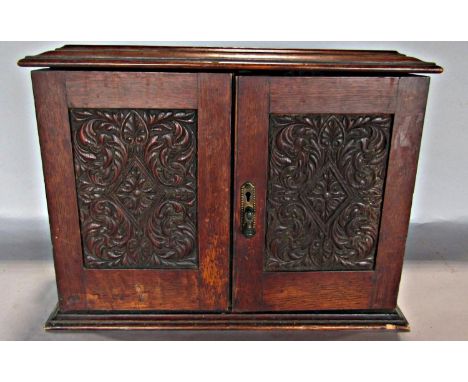 An antique oak smoker’s cabinet with a fitted interior of drawers, pipe racks, and Crown Derby type tobacco jar and two mixin