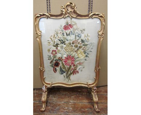 A substantial 19th century firescreen or divider, the carved and gilded framework on scrolled supports enclosing two thread w