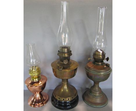 An Aladdin brass oil lamp with chimney but no shade, two further oil lamps with chimneys but no shades. 