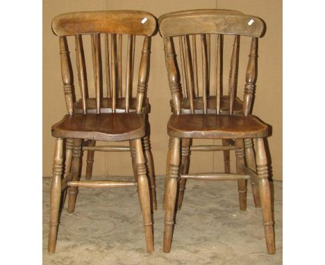 A set of four Windsor stained elm and beechwood stick back kitchen chairs raised on ring turned tapered supports united by st