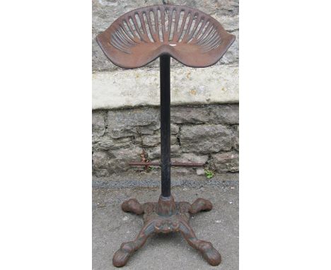 A vintage novel cast iron bar stool with tractor seat, raised on a tubular support and swept paw feet, 80 cm high, the seat 4