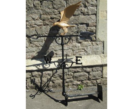 An iron work weather vane complete with wall mounted bracket, north east, south west, raised arrow head pointer, surmounted b