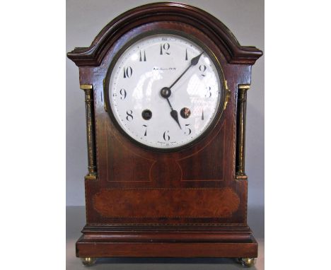 An inlaid Edwardian mahogany mantel clock, with brass column supports, convex enamel dial and two train movement 