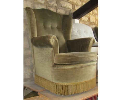 A pair of sage green coloured upholstered armchairs with button backs and scrolled arms, loose cushions and tasselled fringes