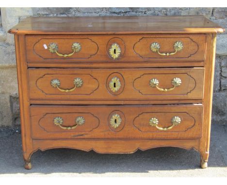 A late 18th century French provincial walnut commode of three drawers, with original brass fittings, raised on short supports