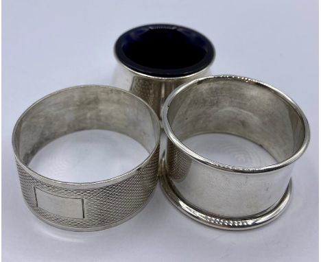 Two hallmarked silver napkin rings and a silver salt with a blue glass liner.