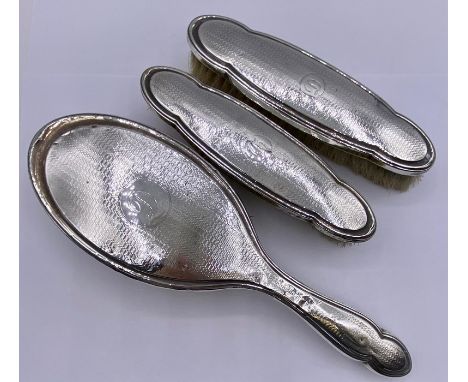 A selection of three silver backed items from a dressing table set.