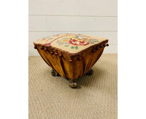 A tapestry foot stool with brass lion paw feet 