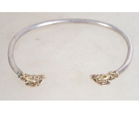 A hallmarked silver bangle bracelet, having detailed gilt rams' heads . Measures 7 cm wide, weighs 12.5 grams.