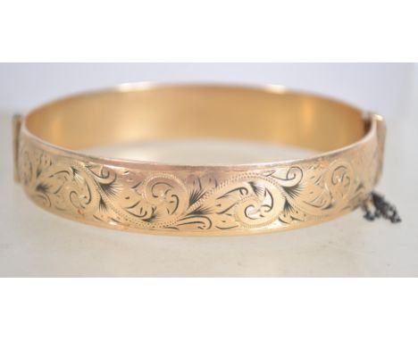 A 9 carat cold metal core bangle bracelet with safety chain having half engraved foliate design, makers Henry Griffith and So