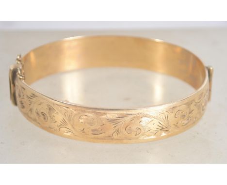 A 9 carat gold metal core bangle bracelet with safety chain having half engraved foliate design, makers Henry Griffith and So