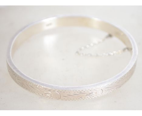 A sterling silver 925 bangle bracelet with safety chain, having full engraved foliate design. Measures 7 cm wide and weighs 1