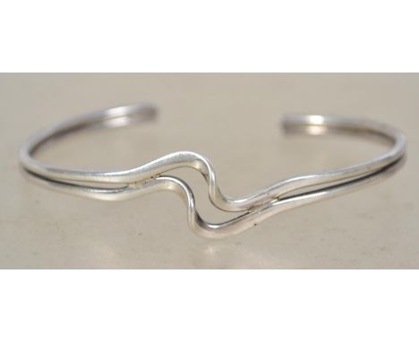 A sterling silver bangle bracelet of crossover form. Rubbed hallmarks. Weighs grams measures 6.5cms wide.