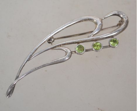 A sterling silver 925 brooch having a wave design with three peridot stones with rollover catch. Weighs 70 grams and measures