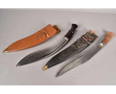 Two 20th Century Kukri knives, one having light wooden grip, complete with two smaller knives and scabbard, together with ano