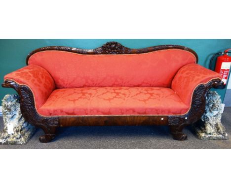 A 19th century Continental carved mahogany framed sofa, with shaped crest rail and opposing eagle arm supports, raised on cor