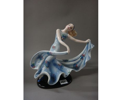 Stefan Dakon for Goldscheider; an Austrian Art Deco figure of a female dancer, circa 1930, modelled in a long blue floral pri