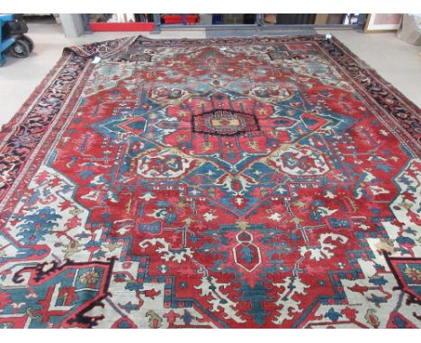 A Heriz carpet, early 20th century, the central stepped medallion on a red ground with white spandrels and tendrils within a 